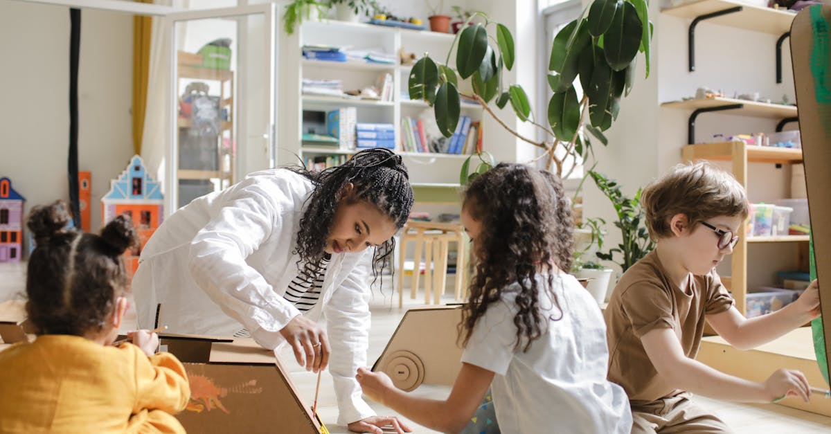 Children engaging in a creative art project with a teacher in a classroom.