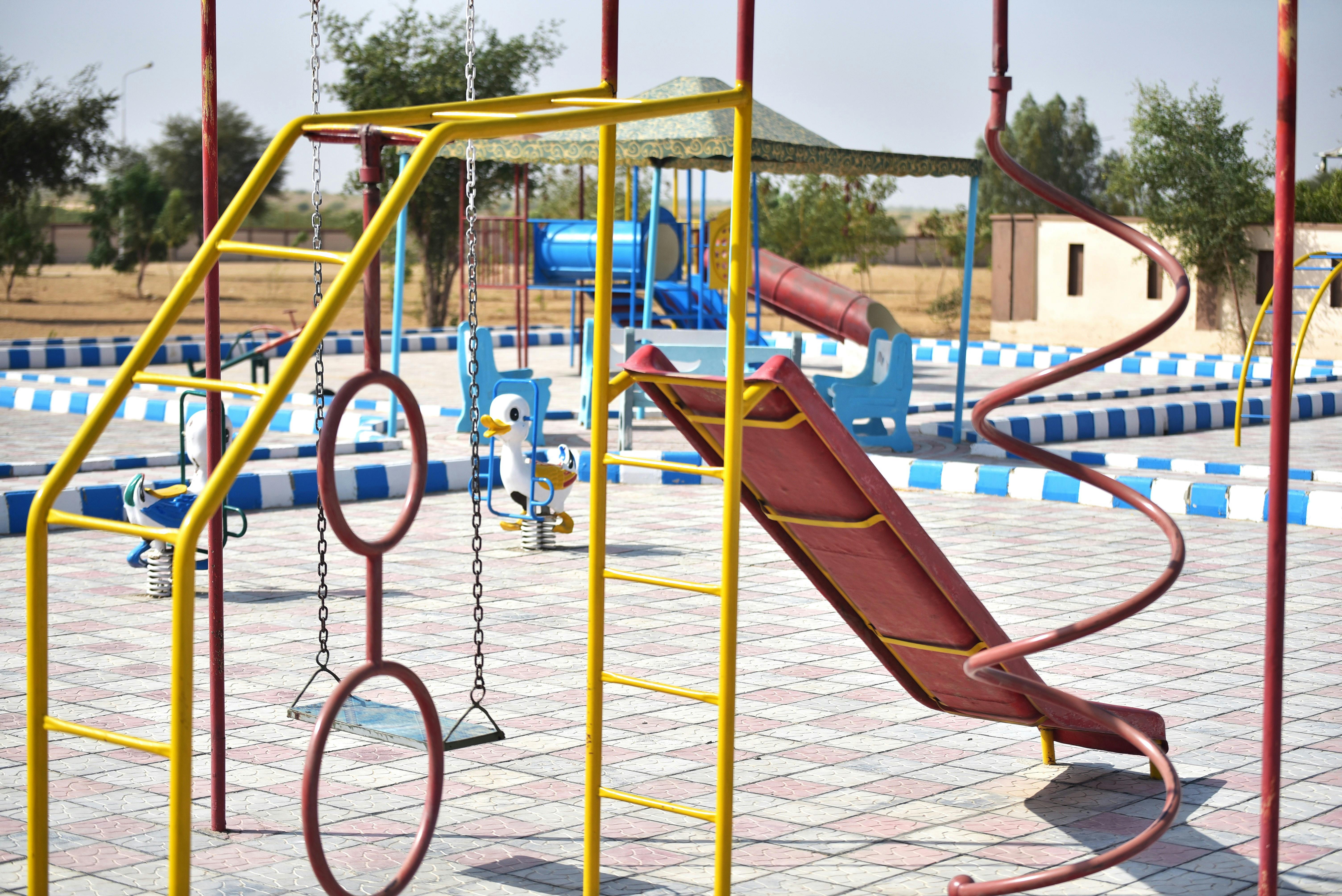 Fenced playground with swings and a slide.